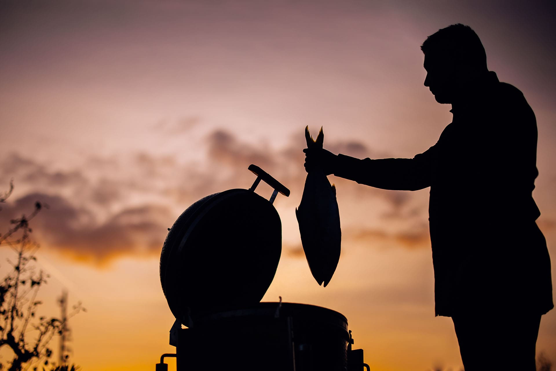 vince houd een vis vast boven de bbq bij restaurant Vinn