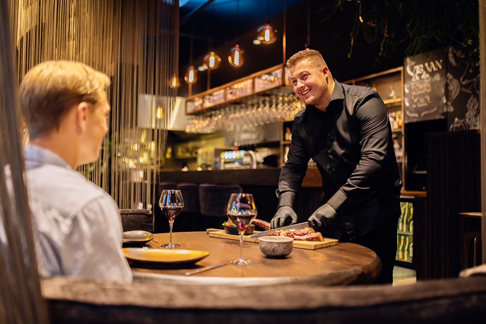 Vince snijd vlees aan tafel in restaurant Vinn